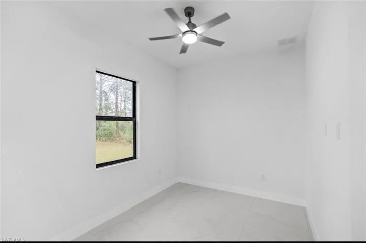 Spare room with light marble finish flooring and ceiling fan