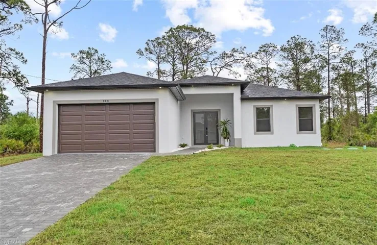 Prairie-style home with stucco siding, an attached garage, decorative driveway, and a front yard