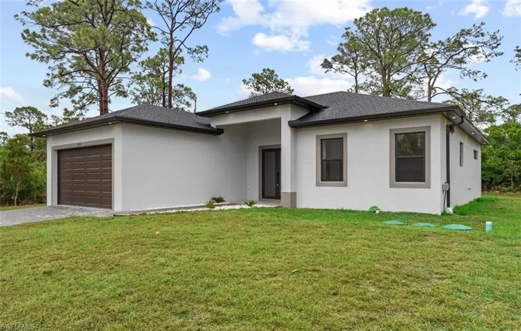 Prairie-style home featuring a front yard, stucco siding, driveway, and an attached garage
