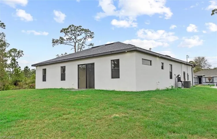 Back of property with a lawn and stucco siding
