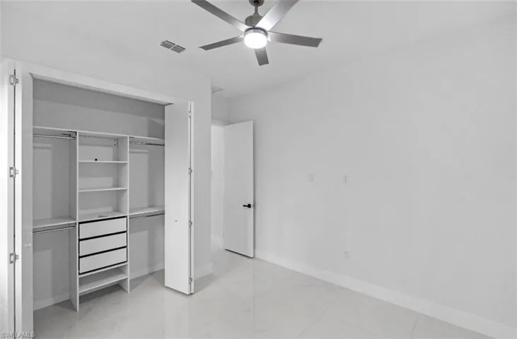Unfurnished bedroom with ceiling fan and a closet