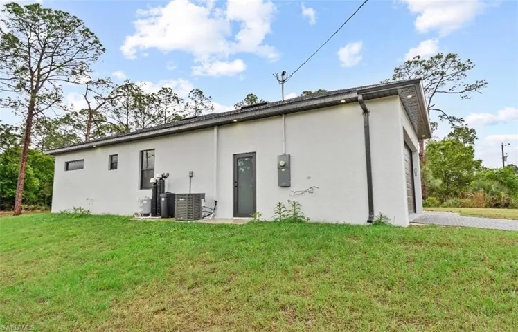 Rear view of property with a lawn and stucco siding