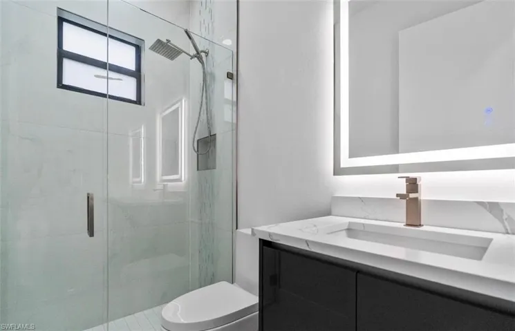 Bathroom featuring vanity and a marble finish shower