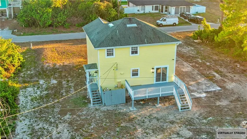 Rear view of property with stairs, a shingled roof, and a deck
