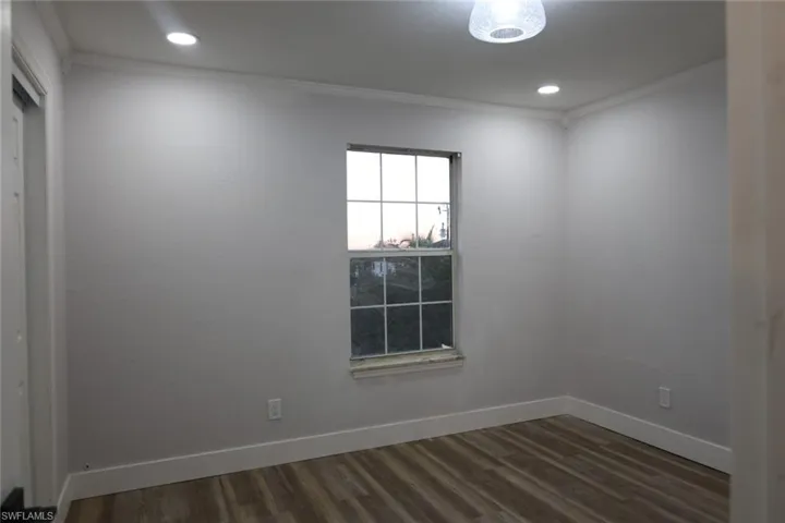 Empty room with crown molding, wood finished floors, and recessed lighting