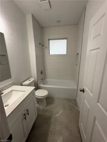 Full bathroom with vanity, shower / bath combination, and a textured wall