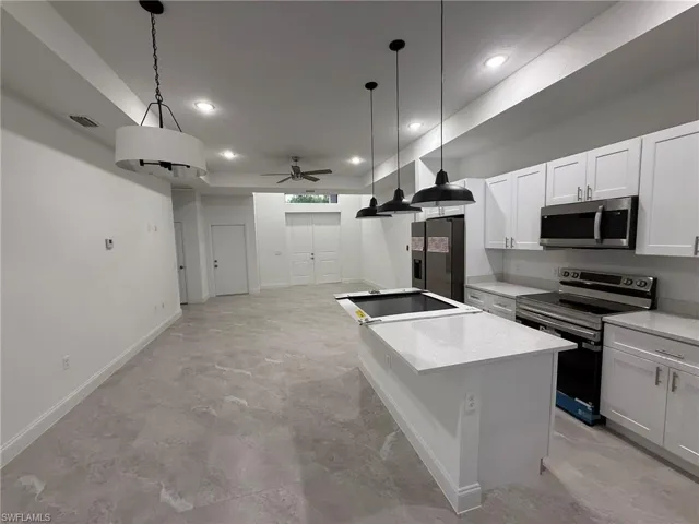 Kitchen with appliances with stainless steel finishes, ceiling fan, decorative light fixtures, recessed lighting, and white cabinetry