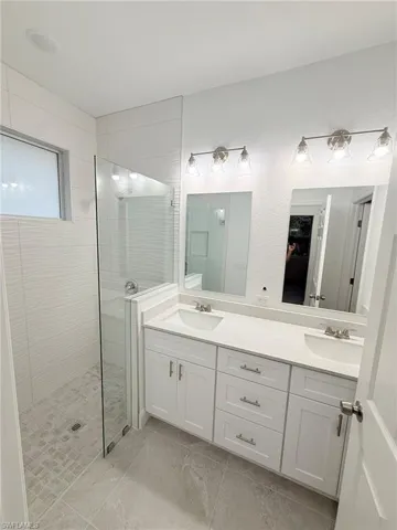 Full bathroom featuring walk in shower and double vanity