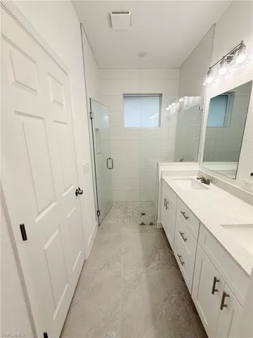 Full bathroom with a stall shower, double vanity, and tile patterned flooring