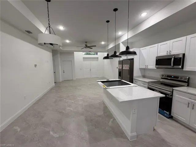 Kitchen with stainless steel appliances, recessed lighting, ceiling fan, a kitchen island, and white cabinets