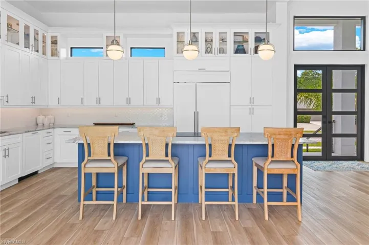 Kitchen with paneled refrigerator, a wealth of natural light, a kitchen island, and light hardwood / wood-style flooring