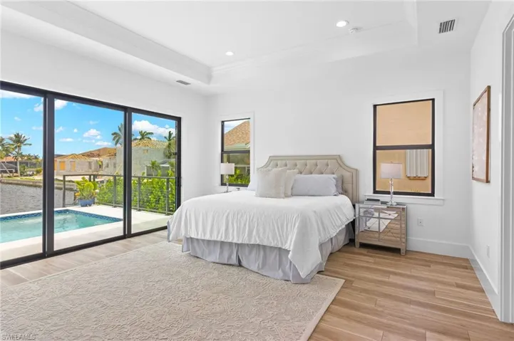 Bedroom featuring a tray ceiling, light wood-type flooring, and access to exterior