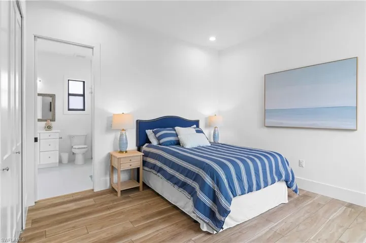 Bedroom with light hardwood / wood-style floors and connected bathroom