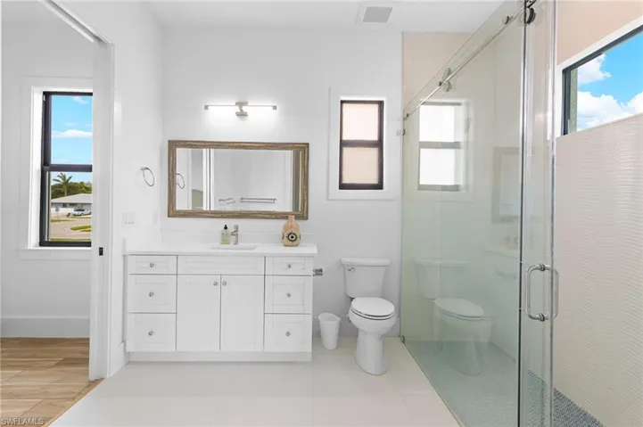 Bathroom with an enclosed shower, vanity, toilet, and tile floors