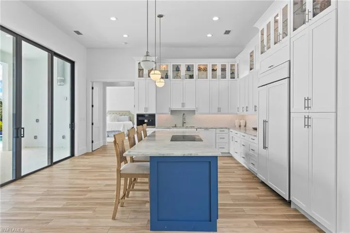 Kitchen with a center island, black appliances, white cabinets, and light hardwood / wood-style floors