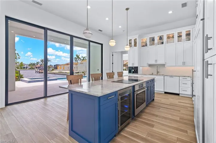Kitchen featuring stainless steel oven, decorative light fixtures, blue cabinets, a center island, and white cabinets