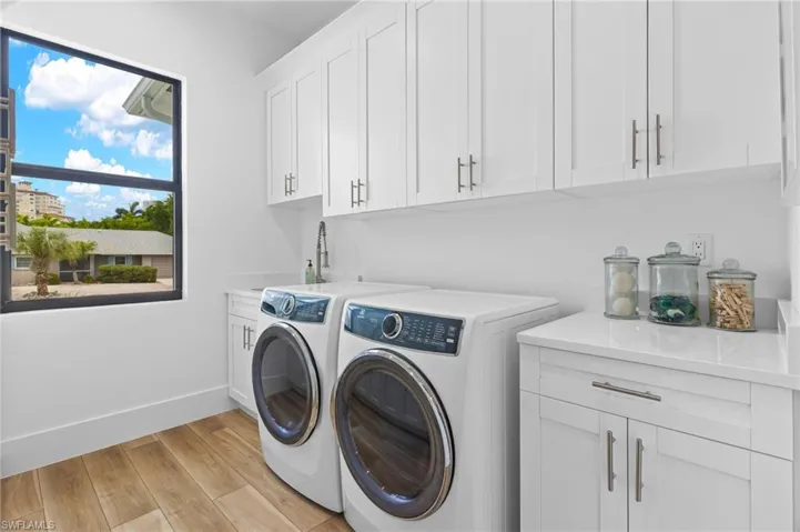 Laundry area with washer and clothes dryer, cabinets, and light hardwood / wood-style flooring