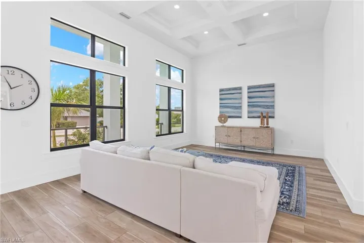 Living room featuring beam ceiling, coffered ceiling, plenty of natural light, and light hardwood / wood-style flooring