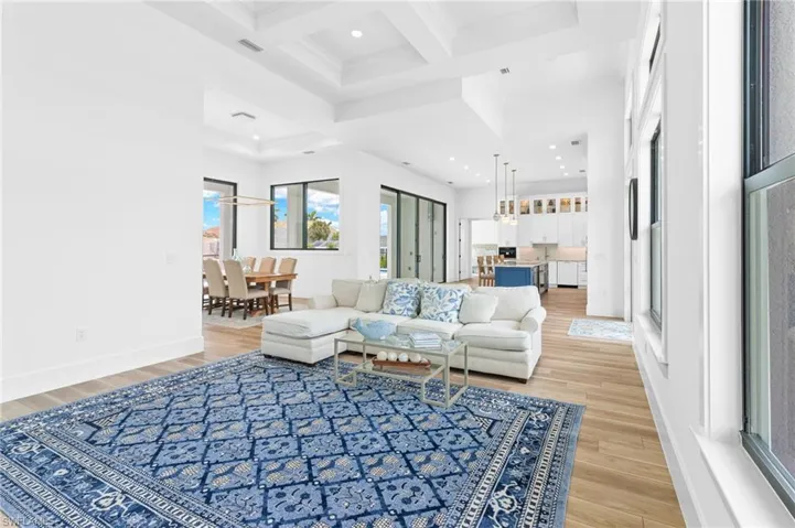 Living room with coffered ceiling, a towering ceiling, light wood-type flooring, and ceiling fan