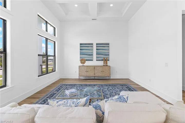 Living room featuring coffered ceiling, beam ceiling, a healthy amount of sunlight, and hardwood / wood-style flooring