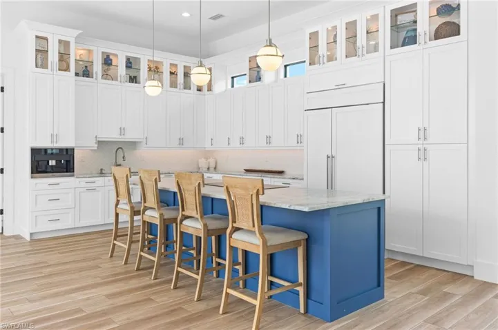 Kitchen featuring a center island, decorative light fixtures, light stone countertops, and light hardwood / wood-style flooring