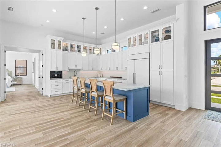 Kitchen with an island with sink, light hardwood / wood-style floors, a kitchen breakfast bar, and paneled refrigerator