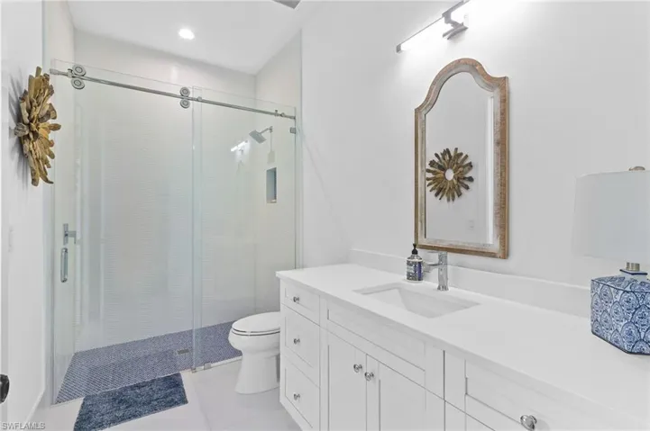 Bathroom with walk in shower, tile flooring, vanity, and toilet