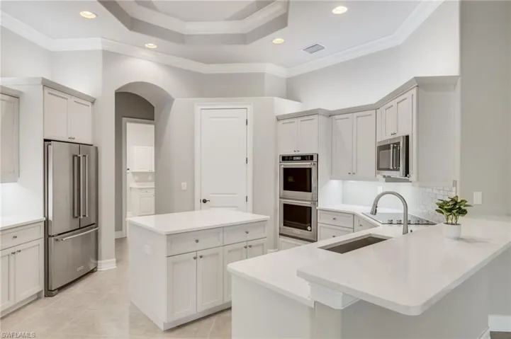 Kitchen with crown molding,center island, stainless steel appliances,  + tile backsplash.