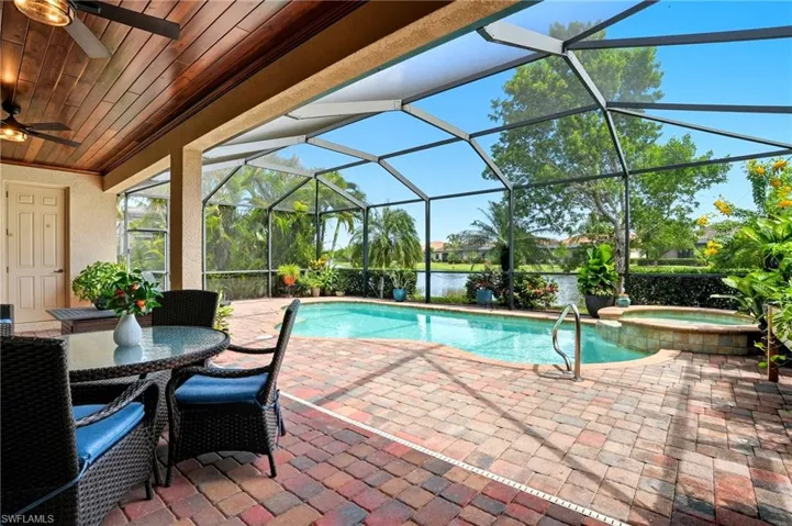 View of swimming pool featuring a water view, a sunroom, a lanai, a patio area, and outdoor dining area