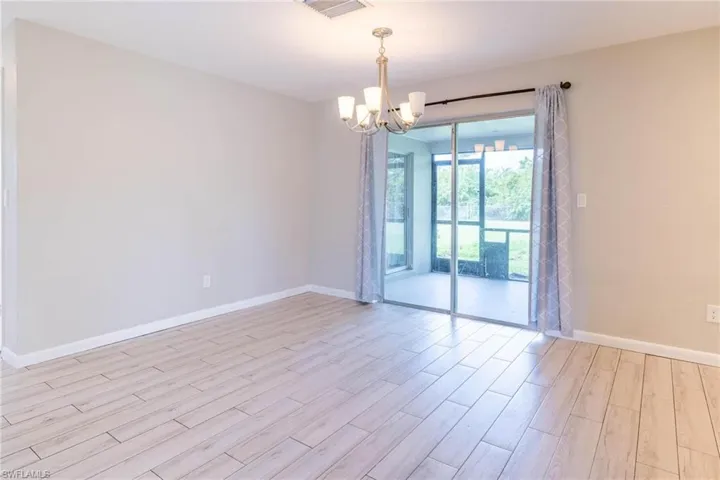 Empty room with a chandelier and light hardwood / wood-style flooring