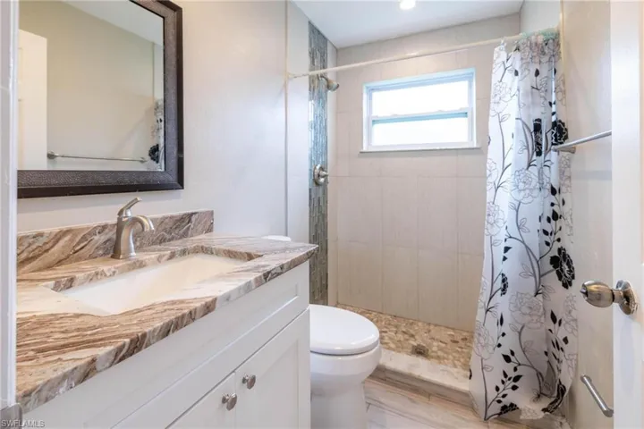 Bathroom featuring curtained shower, hardwood / wood-style floors, vanity, and toilet