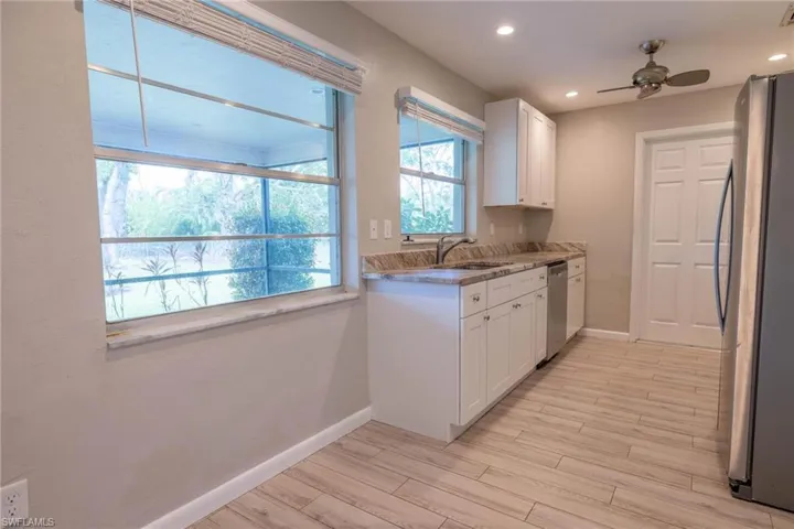 Kitchen with ceiling fan, white cabinetry, stainless steel appliances, and light hardwood / wood-style flooring