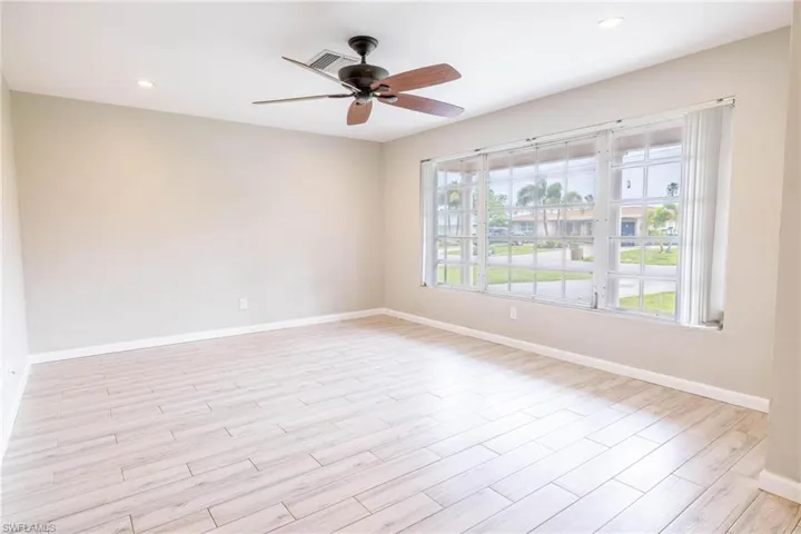 Spare room featuring ceiling fan, light hardwood / wood-style flooring, and a healthy amount of sunlight