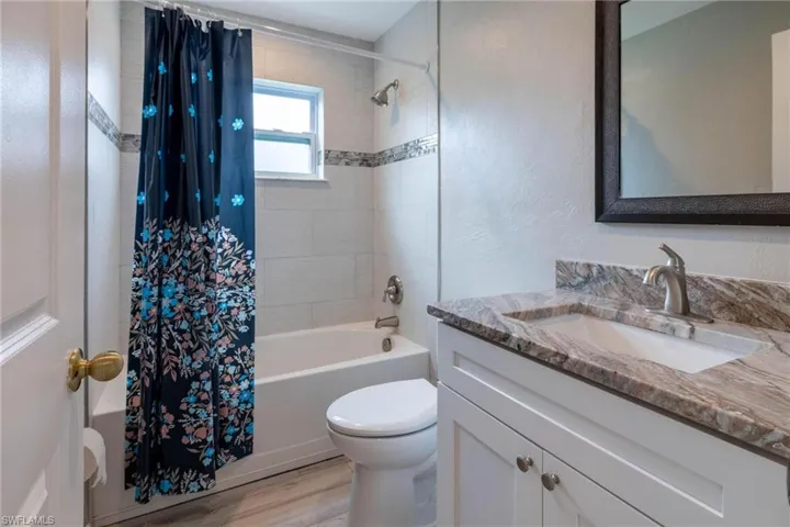 Full bathroom featuring vanity, hardwood / wood-style flooring, toilet, and shower / bath combo with shower curtain