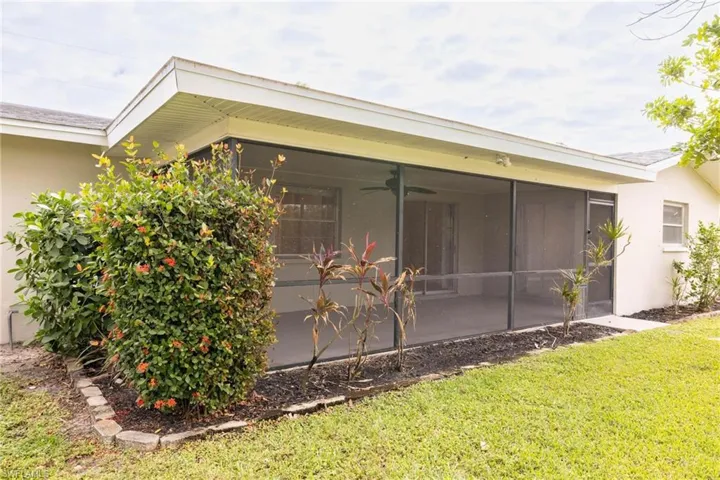View of side of home with a lawn, a sunroom, and ceiling fan