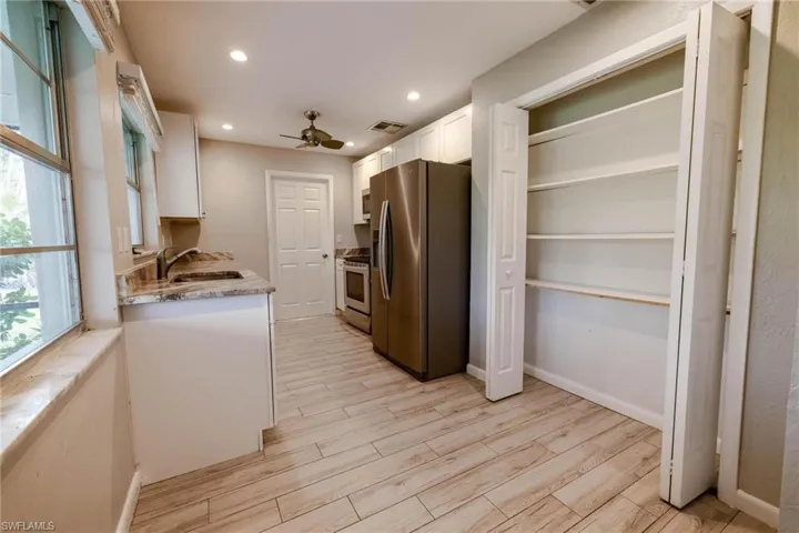 Kitchen featuring appliances with stainless steel finishes, ceiling fan, sink, light hardwood / wood-style flooring, and white cabinets