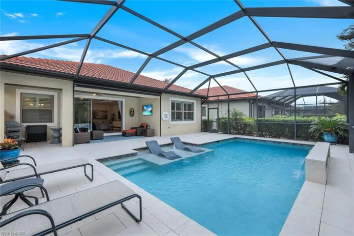 View of pool with an outdoor hangout area, a patio area, and glass enclosure
