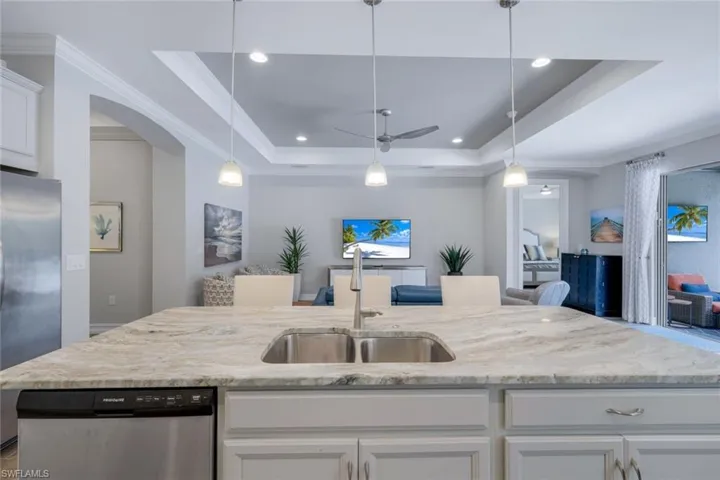 Kitchen with white cabinets, stainless steel appliances, a raised ceiling, and sink