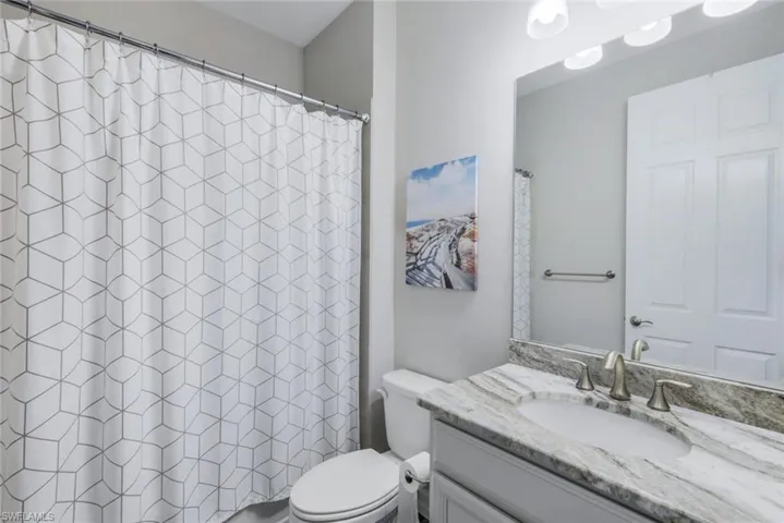 Bathroom featuring toilet, walk in shower, and vanity