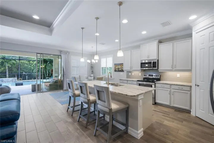 Kitchen featuring stainless steel appliances, a center island with sink, white cabinets, and sink