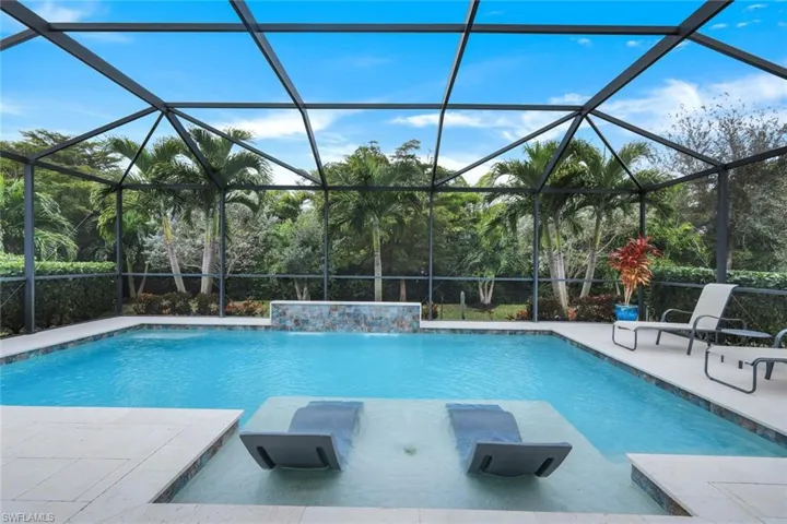 View of swimming pool featuring pool water feature, glass enclosure, and a patio area