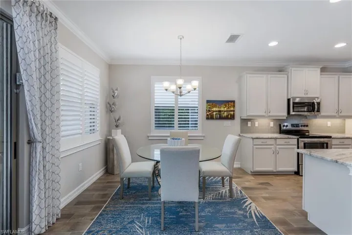 Dining area with crown molding, a chandelier, and wood-type flooring