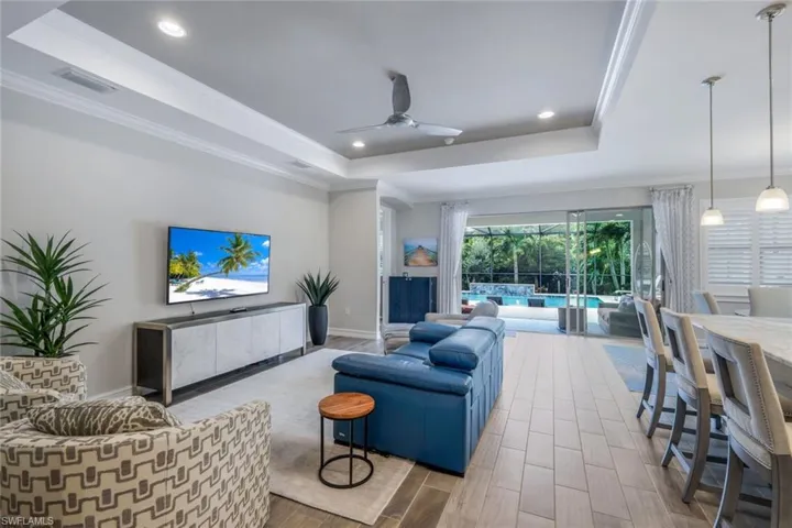 Living room featuring ceiling fan, a tray ceiling, and crown molding