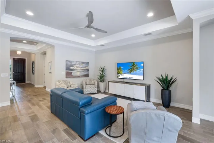 Living room featuring ceiling fan, a tray ceiling, and crown molding