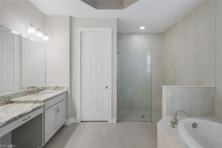 Bathroom featuring tile patterned flooring, separate shower and tub, and vanity