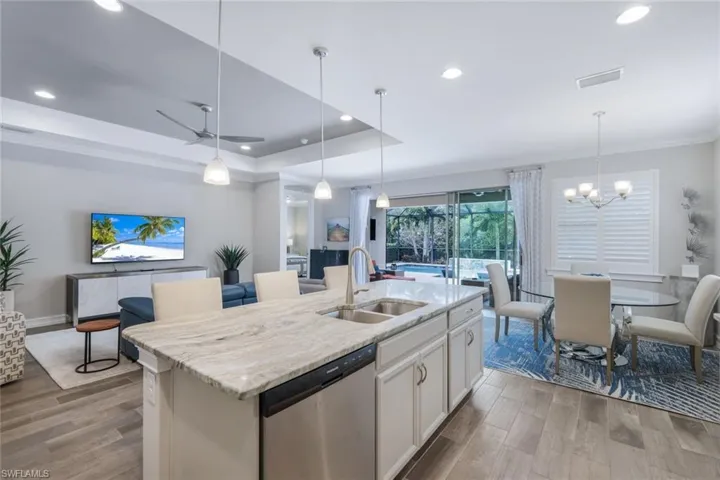 Kitchen with stainless steel dishwasher, sink, a tray ceiling, and an island with sink