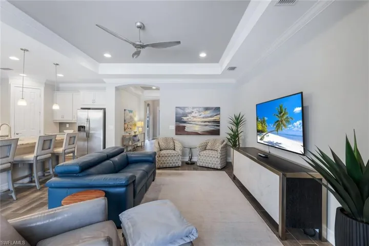 Living room featuring ceiling fan, hardwood / wood-style floors, a tray ceiling, and ornamental molding