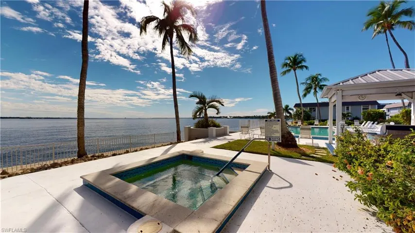 Community pool with a water view, a patio area, and a community hot tub