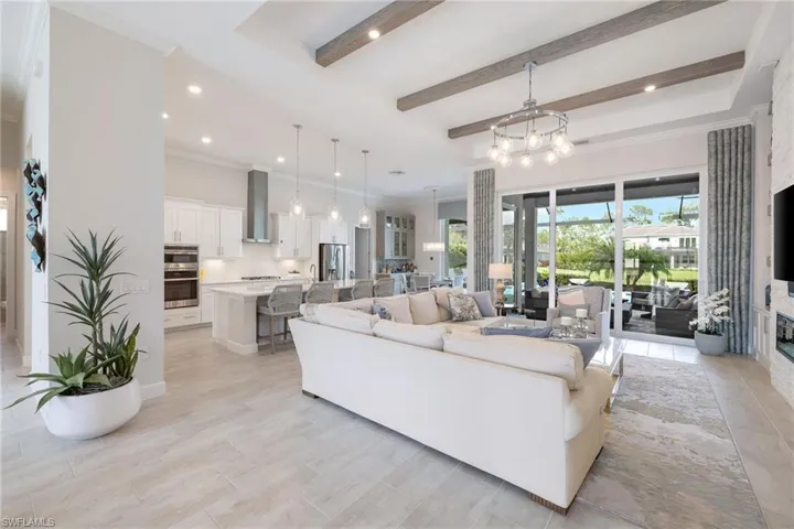 Tiled living room with a wealth of natural light, beamed ceiling, and crown molding