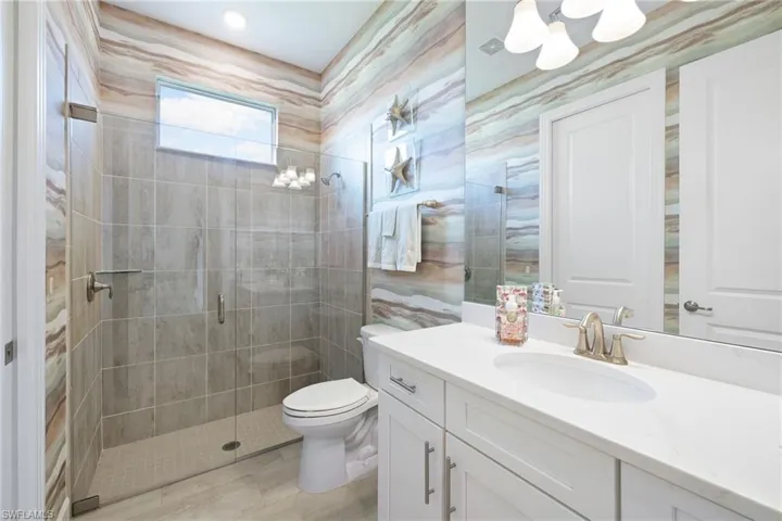 Bathroom featuring walk in shower, large vanity, and toilet